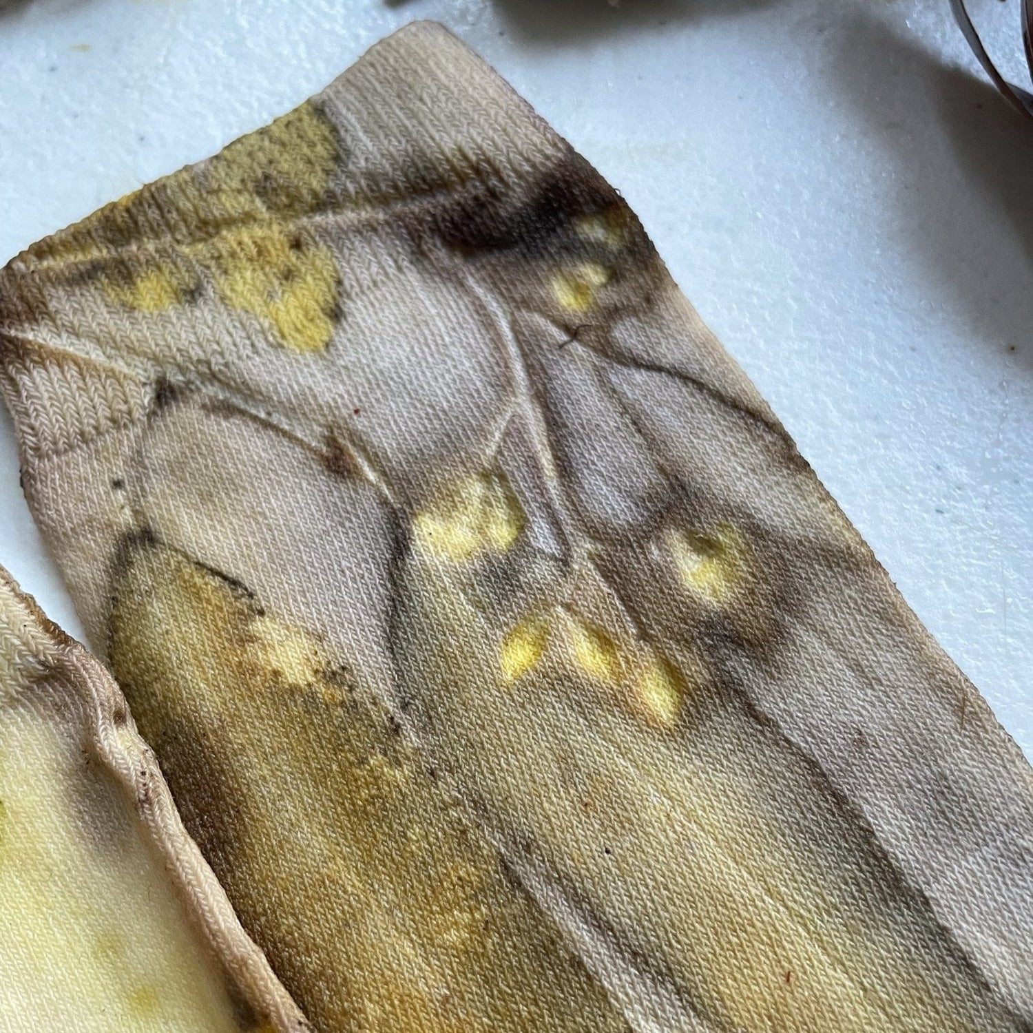 Botanical Eucalypt Socks - Melo Handmades - Botanical socks hand-dyed with eucalyptus leaves in soft gold, brown, and green tones, laid flat on white linen.